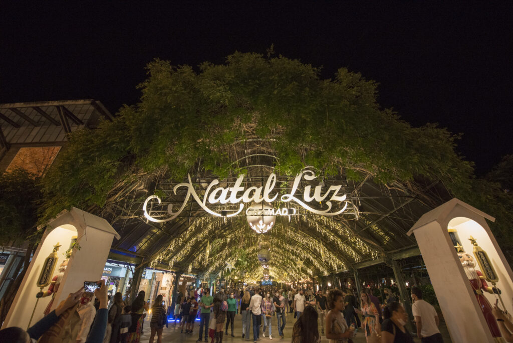 Vale a pena caminhar pelo centro de Gramado à noite? Sim. Nem todas as noites precisam ter uma programação fechada. A região central ganha outra atmosfera depois que escurece. A iluminação das ruas, vitrines, restaurantes e alguns dos principais cartões-postais cria um cenário diferente daquele encontrado durante o dia. A Avenida Borges de Medeiros concentra boa parte desse movimento. Em seus arredores estão locais conhecidos, como a Igreja São Pedro, a Rua Coberta e o Palácio dos Festivais. Assim, uma caminhada pelo centro pode ser combinada com jantar, cafés, chocolates ou simplesmente um período mais tranquilo depois de um dia cheio de atividades. Essa também pode ser uma boa escolha para deixar algum espaço livre na programação. O que fazer à noite durante o Natal Luz? Entre outubro e janeiro, a dinâmica noturna de Gramado muda bastante com o Natal Luz. Além da decoração que transforma diferentes regiões da cidade, o período conta com espetáculos e outras atividades relacionadas ao evento. Consequentemente, quem viaja nessa época precisa ter um cuidado adicional ao montar o roteiro. Dependendo do espetáculo escolhido, será necessário considerar horário de término do passeio diurno, deslocamento até o hotel, jantar e chegada ao local da apresentação. Por esse motivo, não é interessante preencher todos os dias com atividades até o início da noite. Organizar os horários com antecedência permite aproveitar tanto os passeios da Serra Gaúcha quanto a programação natalina sem transformar as férias em uma sequência apertada de compromissos.